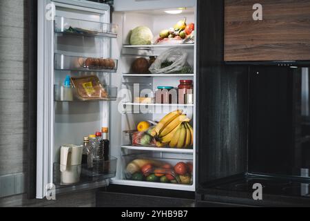 Many different fresh products in modern refrigerator. fresh vegetables on the shelf of the open refrigerator in close-up. Stock Photo