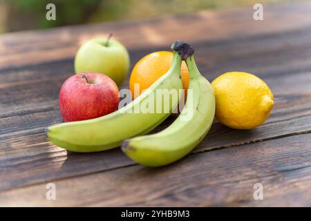 oranges, bananas, pine apple, apples and lemons on wooden table Stock Photo