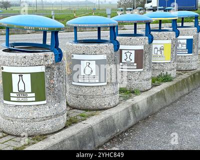 Separate sorting of garbage in Italian freeway parking lot. Stone containers with blue lids. Clean planet and waste, pollution. Glass, paper, metal Stock Photo