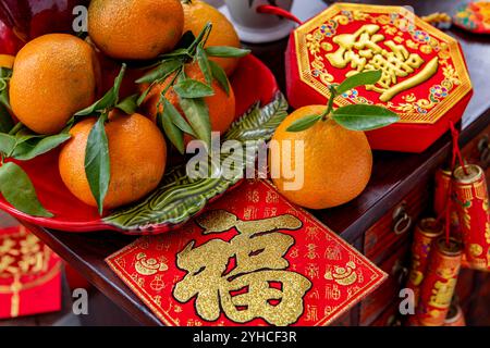 A Chinese New Year concept, background, with a plate of fresh tangerines, health, wealth, good fortune decorations, and red packets on a traditional c Stock Photo