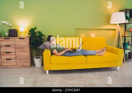 Full length photo of charming pensioner lady lying sofa use netbook sleeping tired dressed green garment house indoors room Stock Photo