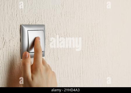 Woman turning light switch on, closeup view Stock Photo