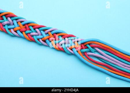 Braided colorful ropes on light blue background, top view. Unity concept Stock Photo