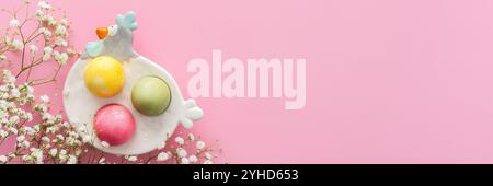 Spring Easter background, multi-colored Easter eggs in a decorative hen with gypsophila flowers on a pink background, copy space, banner Stock Photo