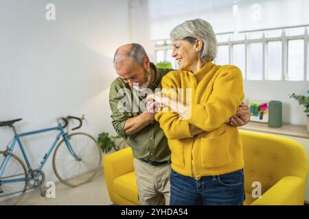Happy mature couple dancing together and smiling at home Stock Photo