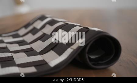 Partially rolled checkered placemat on a wooden surface, highlighting fabric texture Stock Photo