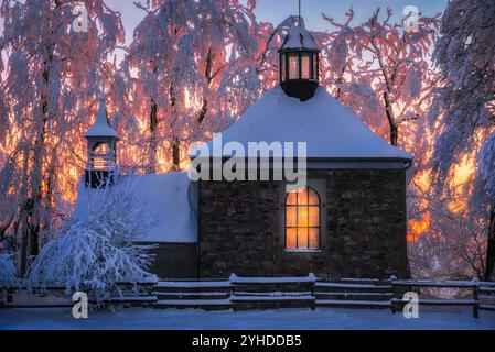 Snow-Covered Chapel at Sunset with Warm Light in Winter Forest in High Fens of Belgium Stock Photo