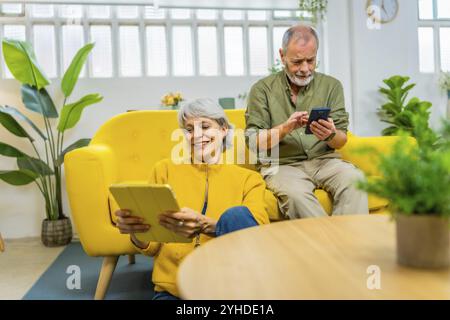 Senior couple using diverse devices and technology together at home Stock Photo