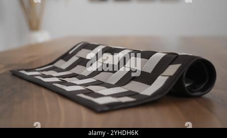 Checkered placemat rolled up on a wooden table, showing its pattern and texture Stock Photo
