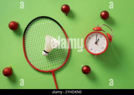 Christmas badminton concept with racket, red ball and white feather badminton shuttlecocks on green background. Copy space. Top view. Xmas greeting ca Stock Photo