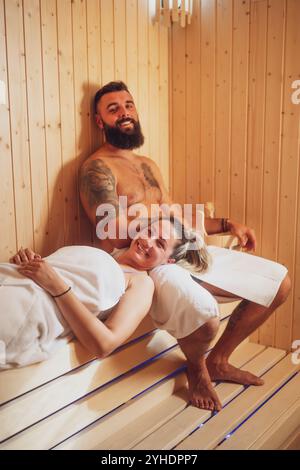 Adult couple is relaxing at sauna. Man and woman enjoying healthy treatment. Stock Photo