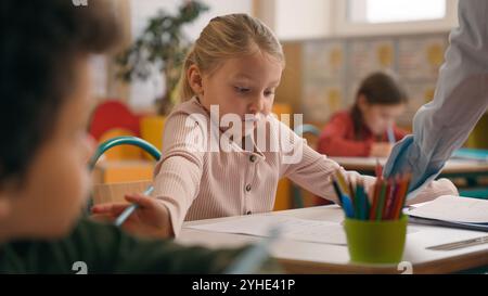 Caucasian woman teacher in elementary school teach children class kids writing task in classroom knowledge studying primary education lesson female Stock Photo