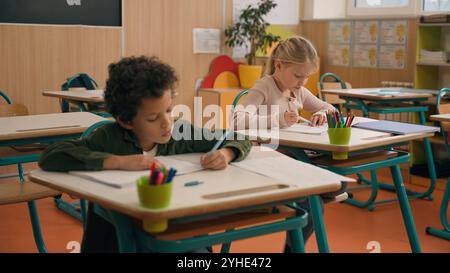 Elementary primary education studying in school multiracial pupils multiethnic children diversity kids African American son boy Caucasian girl Stock Photo