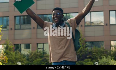 African American happy success winner student guy university education learning college test exam good result man ethnic male in city outdoors win Stock Photo