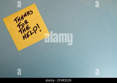 Yellow sticky note on a blue background with handwritten text that reads Thanks for the help, in black marker Stock Photo
