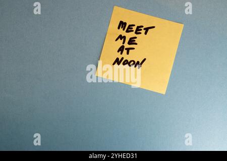 Meet me at noon sticky note on a blue background Stock Photo