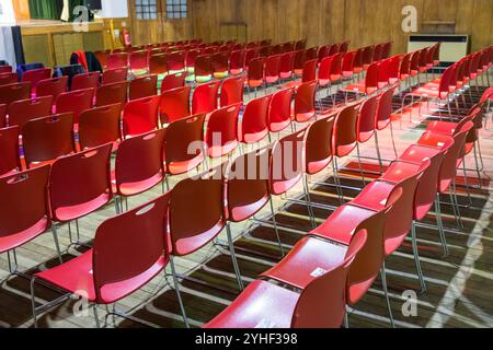 Rows of empty plastic red chairs in a hall Stock Photo