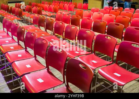 Rows of empty plastic red chairs in a hall Stock Photo