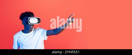 Young man interacts with virtual reality headset in a vibrant studio setting Stock Photo