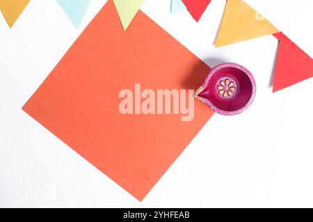 A vibrant orange paper note with diya and decorative flag on a white background. Ideal for Diwali greeting cards, invitations, holiday decorations. Stock Photo