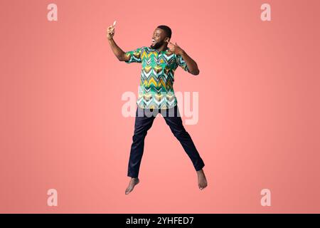 Happy black guy in african costume taking selfie Stock Photo