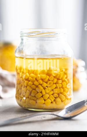 Canned sweet corn in jar on a kitchen table. Stock Photo