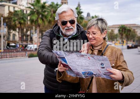 Mature Caucasian tourist couple looking at a travel map searching for a place on their vacation. Stock Photo