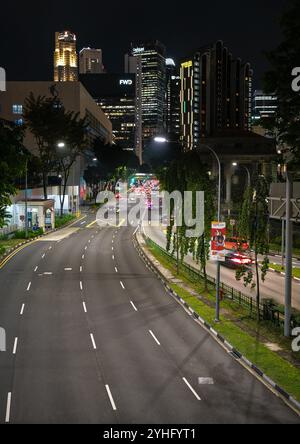 An empty road at nighttime heading to the city in Singapore with skyscrapers in the distance. Stock Photo