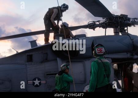 Sailors assigned to the 'Tridents' of Helicopter Sea Combat Squadron (HSC) 9, conduct preflight checks on an MH-60S Seahawk on the flight deck of the world's largest aircraft carrier, USS Gerald R. Ford (CVN 78), Nov. 9, 2024. The Gerald R. Ford Carrier Strike Group is underway in the Atlantic Ocean completing Group Sail. Group Sail is the first at-sea integrated phase training event during a routine deployment training cycle. It is designed to challenge the Gerald R. Ford CSG’s ability to use the capabilities of the USS Gerald R. Ford (CVN 78), USS Winston S. Churchill (DDG 81), Carrier Air W Stock Photo