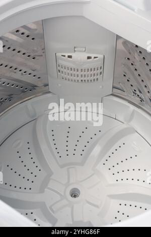inside view of top loading washing machine white steel drum in close-up with perforated pattern for water flow Stock Photo