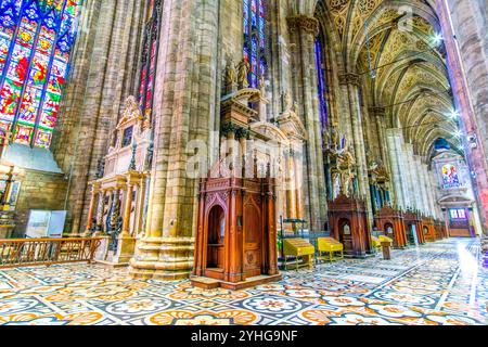 MILAN, ITALY - APRIL 8, 2022: The side aisle with line of confessional booths and votive candle stands, Milan Duomo, on April 8 in Milan, Italy Stock Photo