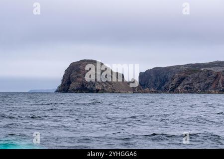 A towering rock stands proudly in the ocean, its imposing presence a striking feature of the rugged coastal landscape. Stock Photo