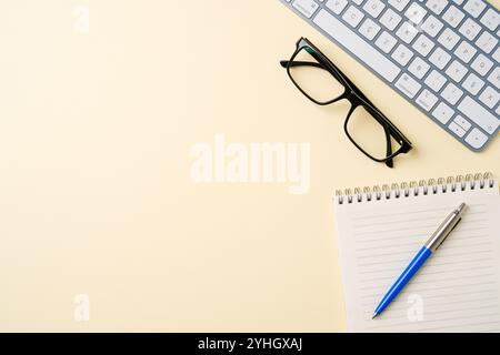 Office desk with computer keyboard, glasses, notebook and pen. Top view with copy space. Flat lay Stock Photo
