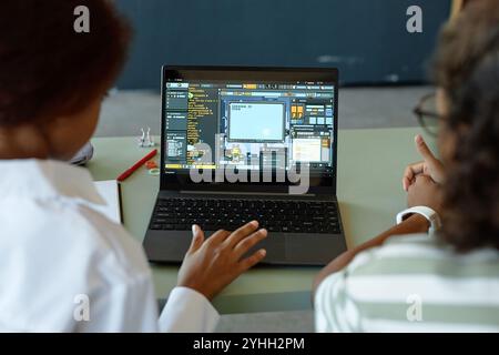 Over shoulder view of two kids using laptop in school classroom together with playful IT programming lesson on screen copy space Stock Photo