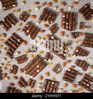 Broken chocolate pieces with nuts and raisins on a stone background top view Stock Photo