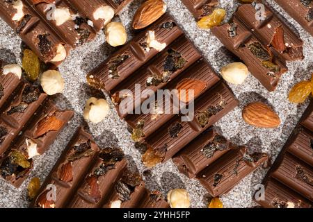 Broken chocolate pieces with nuts and raisins on a stone background top view Stock Photo