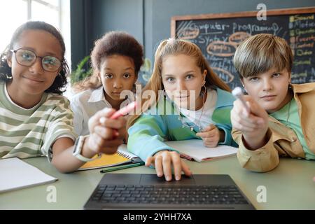 POV shot of group of curious young children using laptop and looking at computer screen in school class Stock Photo