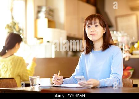 Woman checking her schedule book while looking at her mobile phone in a café Stock Photo