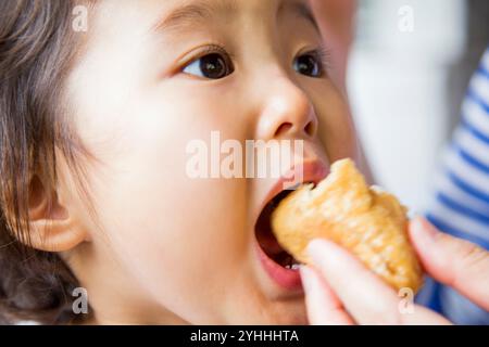 Girl putting Inari-zushi in her mouth Stock Photo