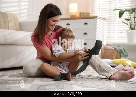 Mother helping her daughter to put tights on at home Stock Photo