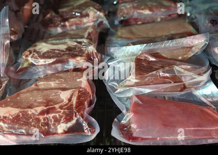 Beef steaks are kept in a special refrigerator before being cooked. Steaks in airtight packaging in the refrigerator. Maturing steaks before cooking. Stock Photo