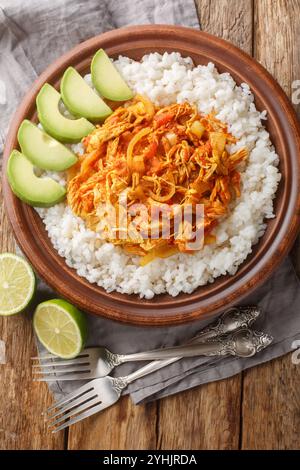 Chicken Tinga shredded and cooked with onion, garlic, tomatoes and chipotle peppers served with rice and avocado closeup in plate on the table. Vertic Stock Photo