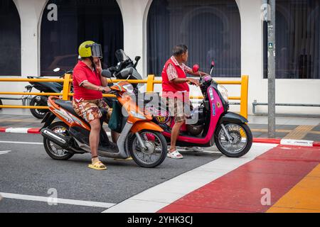 Local thai people ride motorbike. Motorcyclists awaiting traffic light on the road. People riding their motorbikes in old town Phuket Thailand-Street Stock Photo