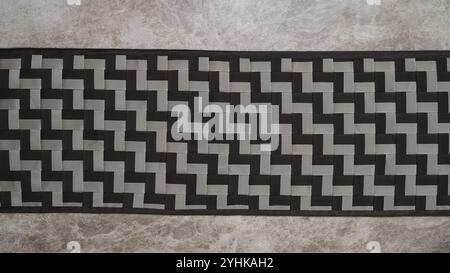 A rectangular piece with a black and gray geometric zigzag pattern on a textured surface Stock Photo