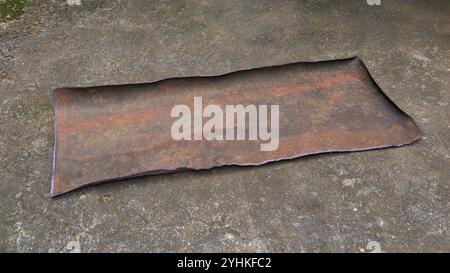 used old weathered dirty fabric carpet on cement surface, faded, frayed dirt or dust collected and stiff mat in soft focus Stock Photo