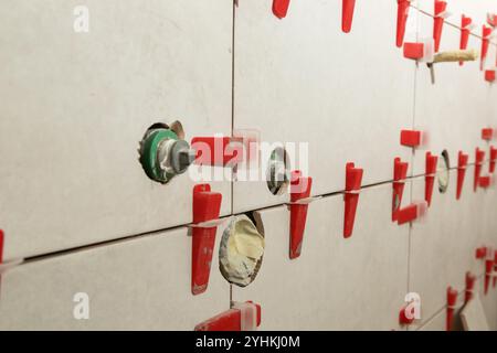 Flat wall plastic tile leveling system. Process of installation of tiles in the bathroom step by step. DIY home improvement. Stock Photo