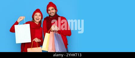 Winter Shopping. Happy Young Couple In Knitted Hats Holding Bright Shopper Bags Stock Photo