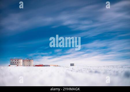 Concordia Station, shelter/VSAT building, sky veiled in cirrus clouds, snowy ground blurred. The two towers of Concordia Station. The square building Stock Photo
