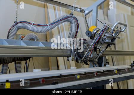 An industrial woodworking setup with robotic CNC machine arm equipped with motor dust collection hose used in production wooden panels doors Stock Photo