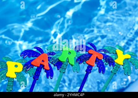 Party on the blue background of the pool. Festive decoration of a palm tree on a background of blue water. Stock Photo